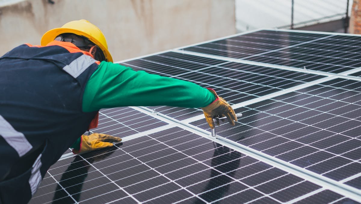homem instalando painel de energia solar em residência