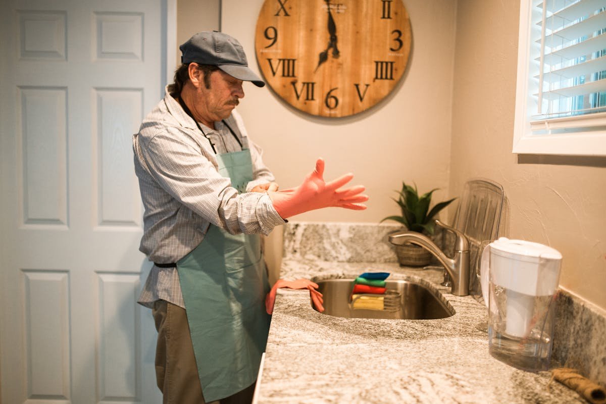 Senior Man Wearing a Gloves Standing in Front of a Sink