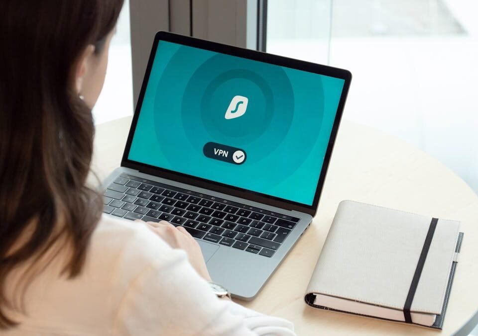 Firewall em casa: vale a pena investir? A woman working on a laptop with a VPN icon on screen for secure online browsing.