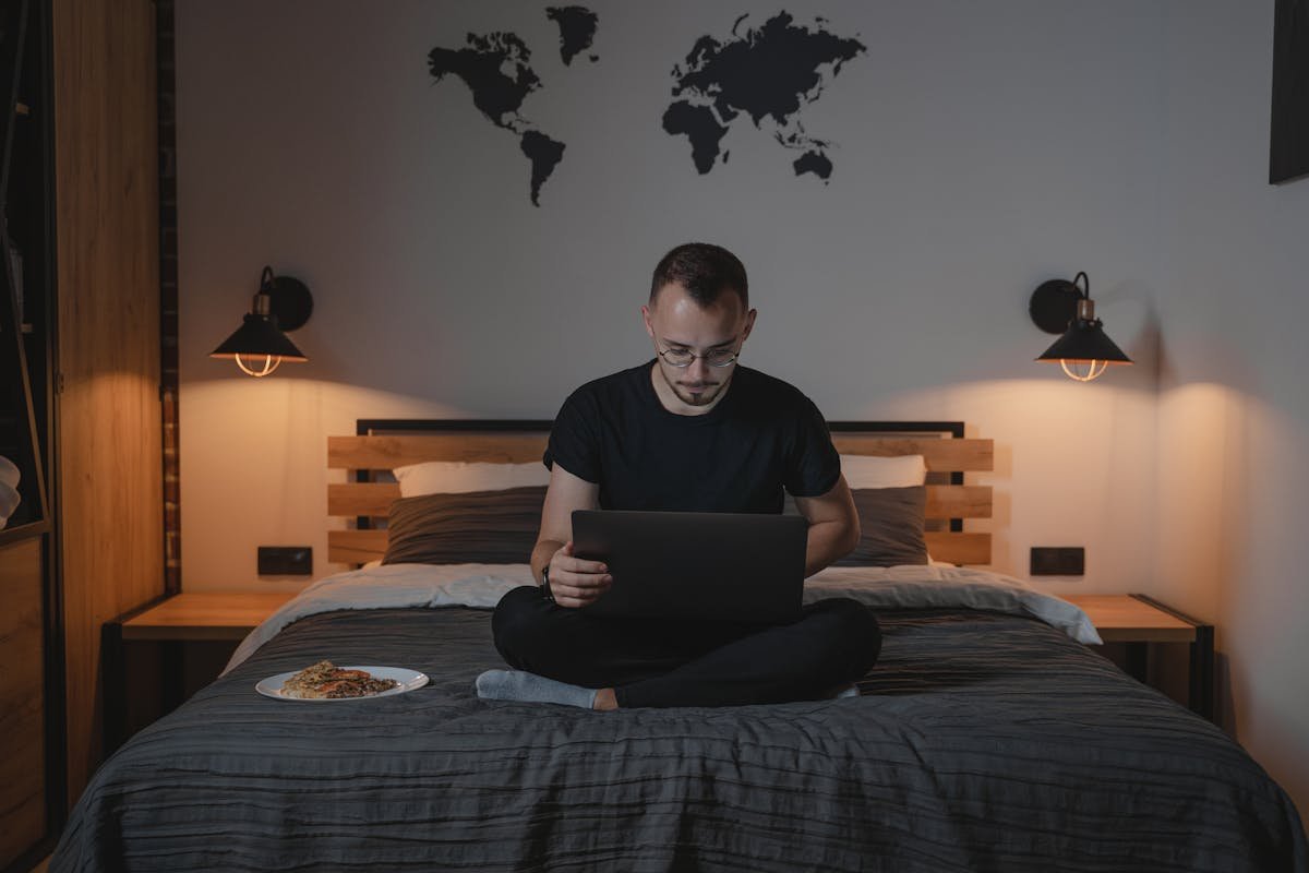 Home office seguro: dicas para empreendedores A Man Using a Laptop while Sitting on a Bed