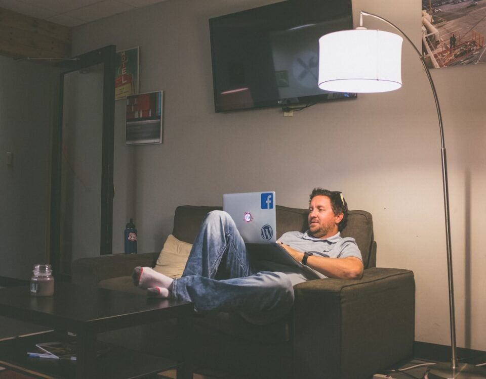 Produtos que ajudam a criar um ambiente mais funcional man lying on couch while using laptop computer