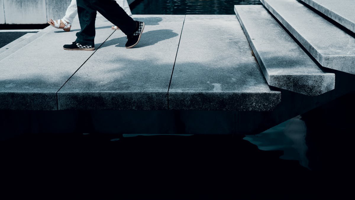 Políticas públicas para a segurança residencial Abstract view of people walking on a modern urban walkway with shadows and steps.