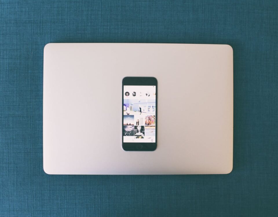 Privacidade no Instagram: Proteja sua casa nas redes Flat lay of a smartphone on a laptop with social media photos on screen.