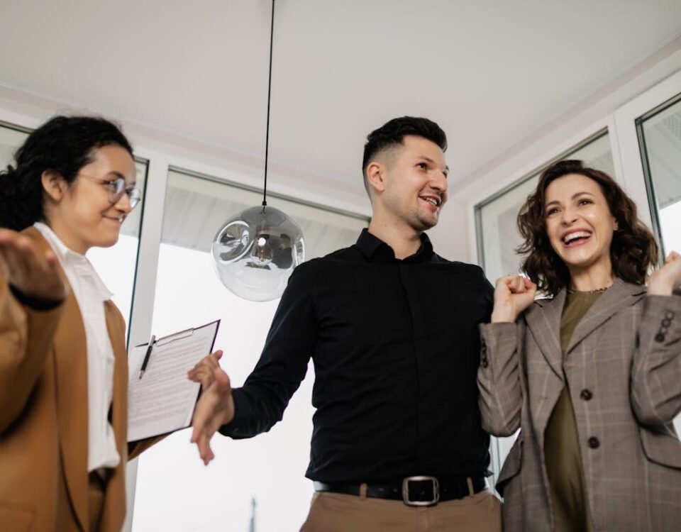 Seguro residencial ou seguro de vida: Qual priorizar? A joyful couple and their realtor celebrate successfully buying a new house indoors.