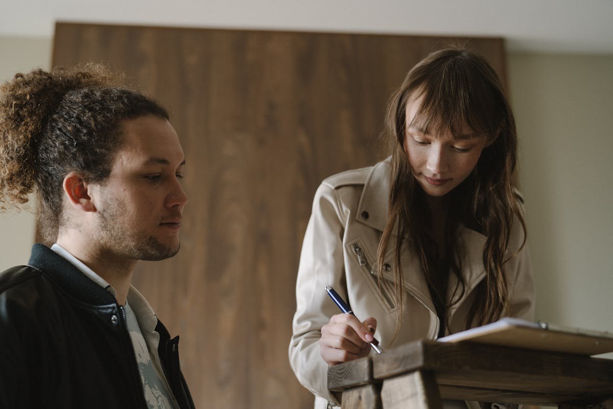 Seguro residencial ou seguro de vida: Qual priorizar? A young couple reviews and signs real estate documents indoors.