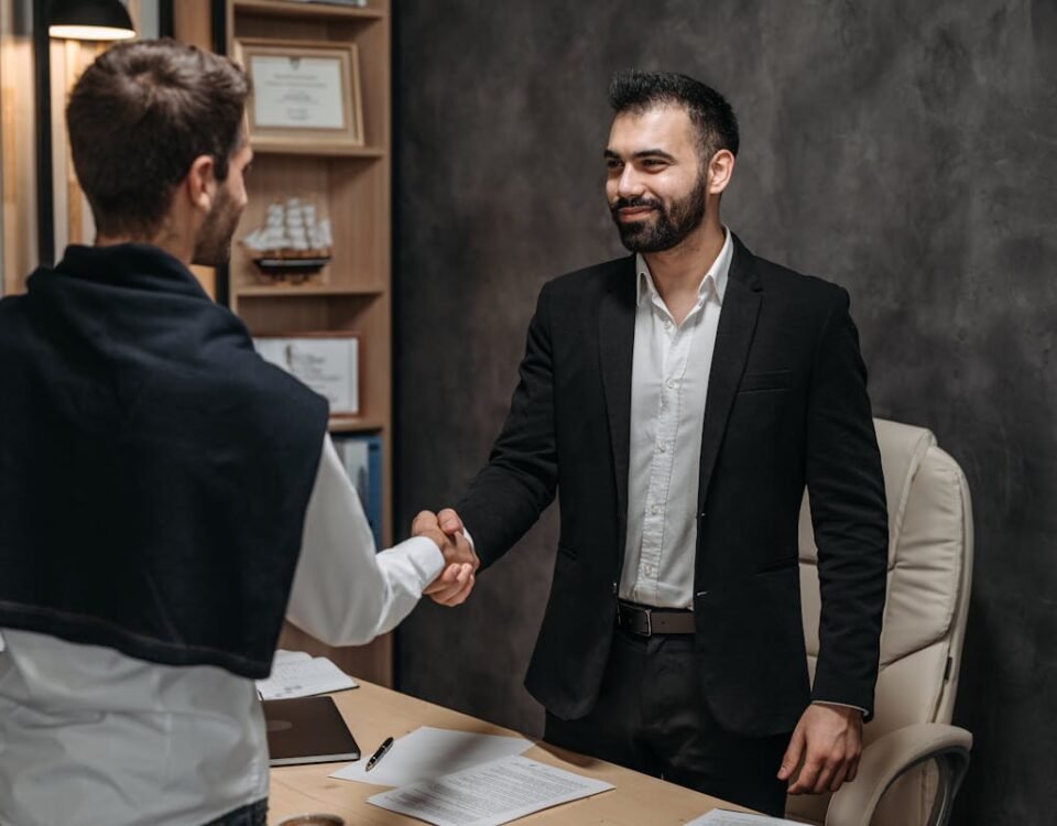 Dicas de segurança jurídica ao contratar um advogado criminalista Two businessmen shaking hands in a modern office, sealing a business deal.