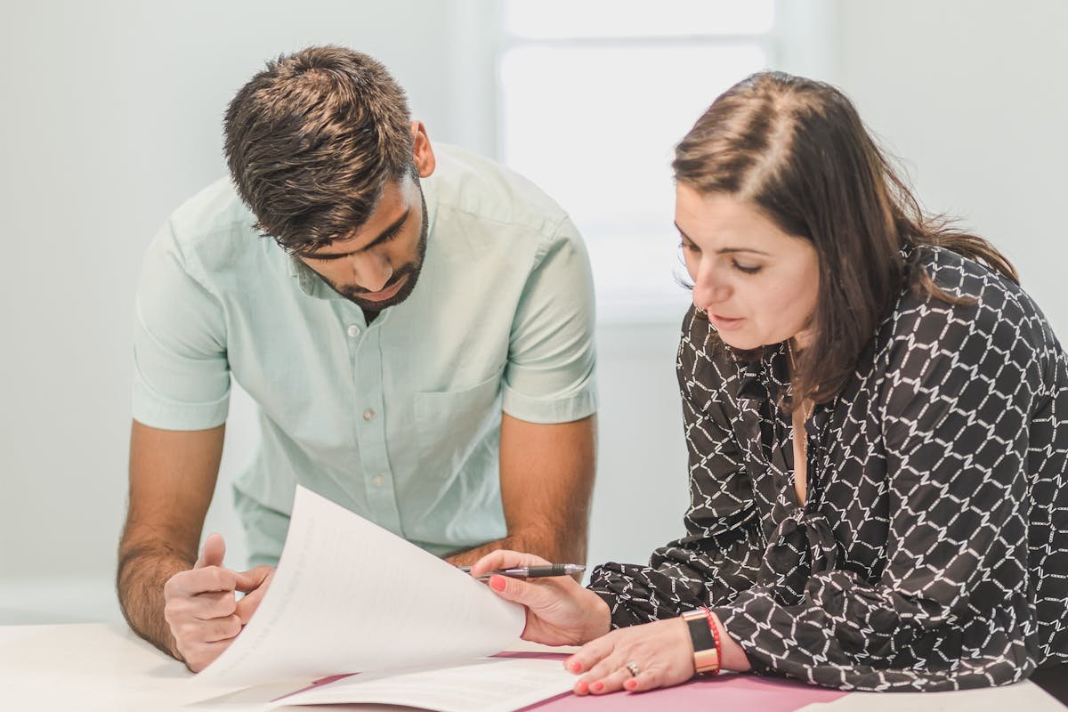 Onde guardar sua CNH em casa com segurança Real estate agent assisting first-time homebuyer with documents inside a bright room.