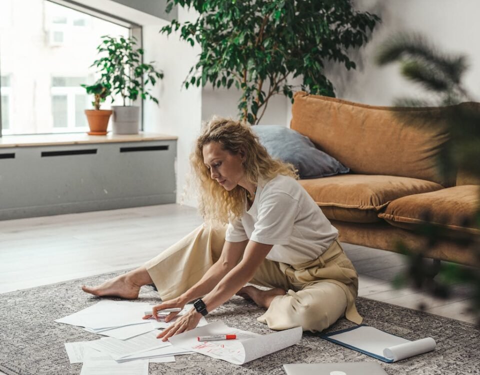 Onde guardar sua CNH em casa com segurança A woman sitting on the floor of her living room working on documents and papers, embodying a comfortable work-from-home atmosphere.