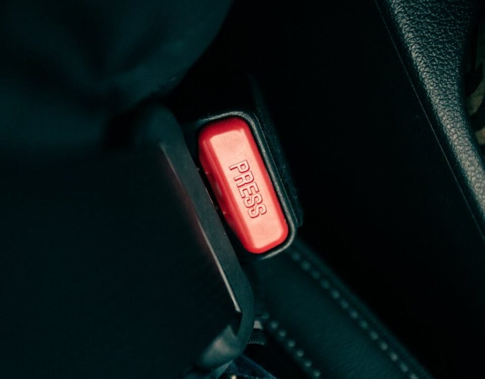 CNH e seguros: O que considerar ao dirigir Detailed view of a car seatbelt buckle with a red press button.