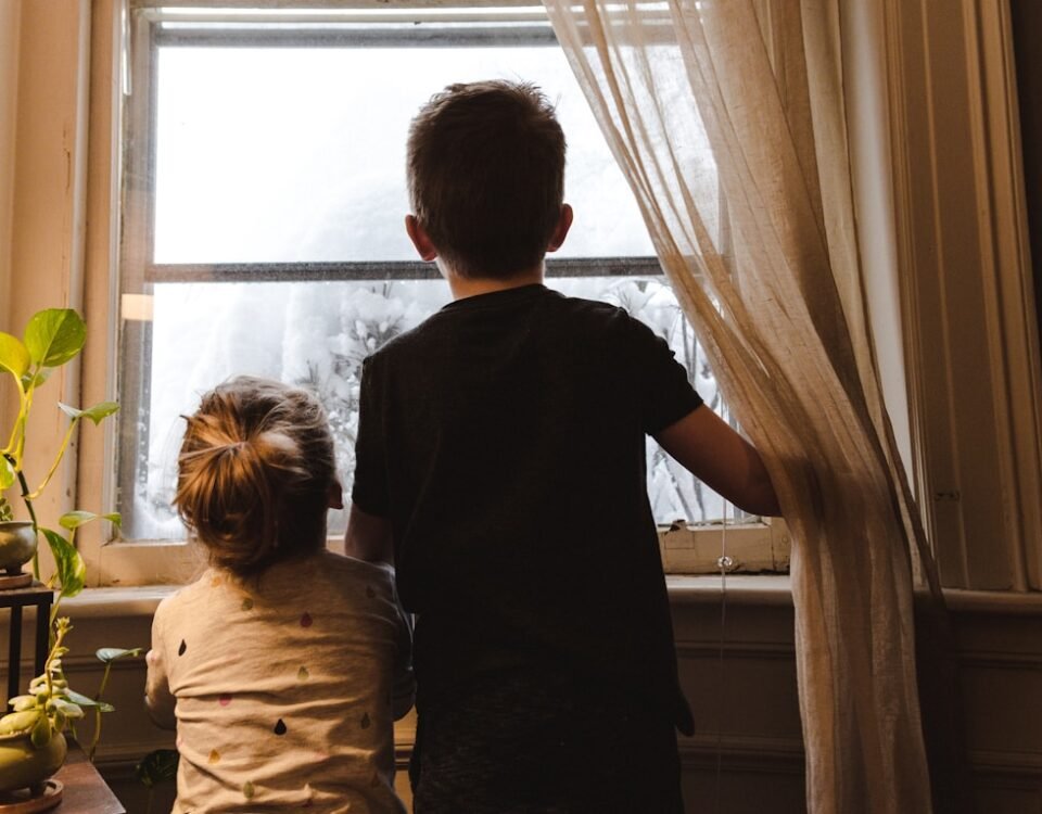 Principais dicas para pais de primeira viagem deixarem a casa mais protegida para os pequenos boy and girl standing near window looking outside