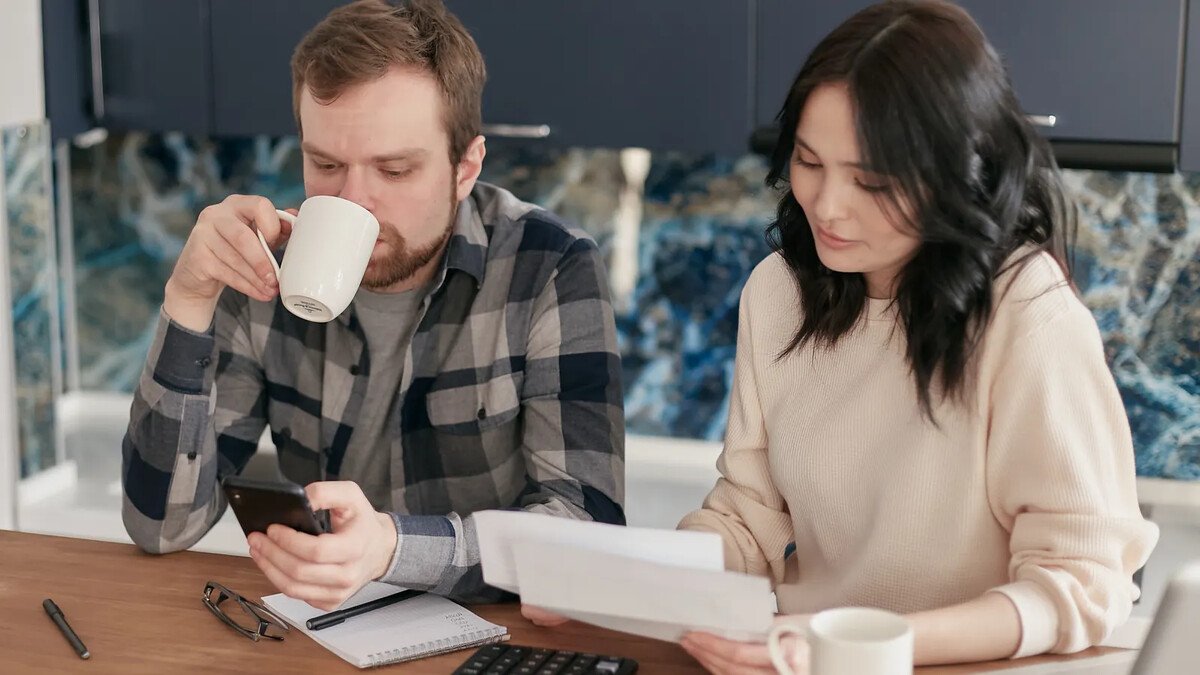 Casal sentado à mesa revisando contas e papéis da casa
