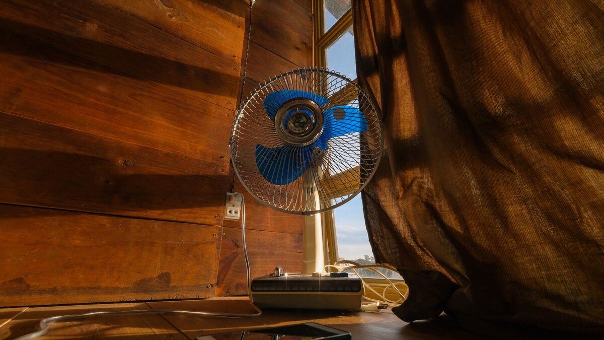 Ventilador elétrico posicionado ao lado de uma janela