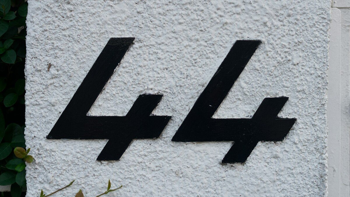 Número e nome na fachada de casa: qual material dura mais? Número 44 preto aplicado em parede branca texturizada