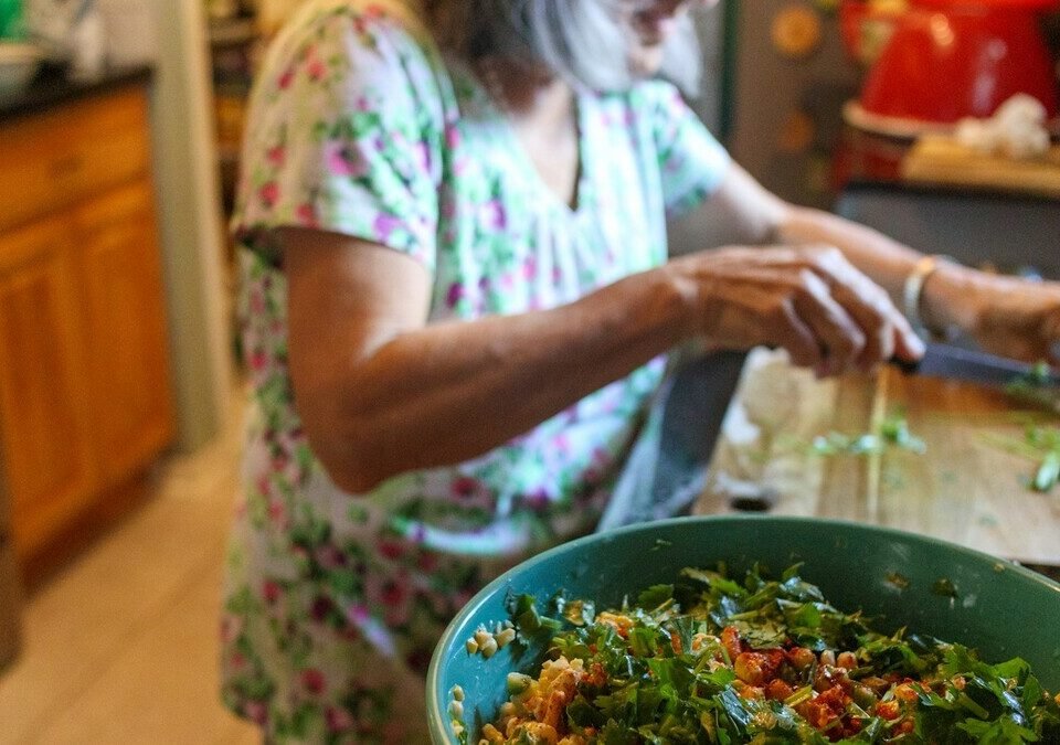 Mulher cortando legumes para uma salada em uma cozinha