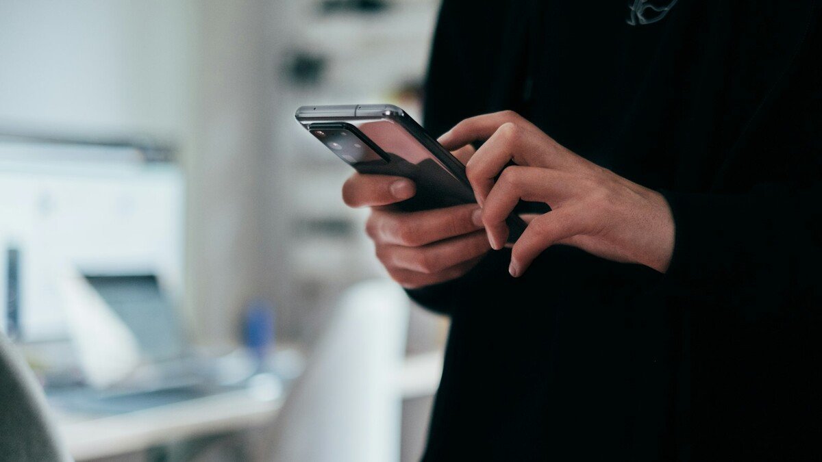 Saldo de bets na Caixa: como não cair em golpe na devolução Pessoa segurando um smartphone com a tela acesa