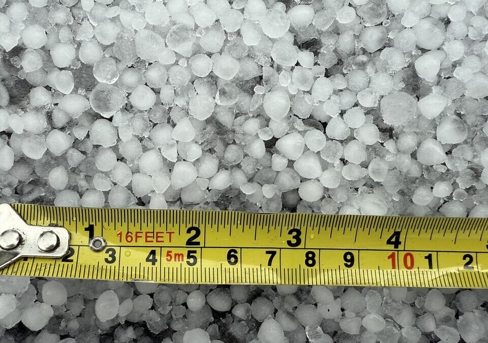 Pedras de granizo acumuladas no chão ao lado de uma trena